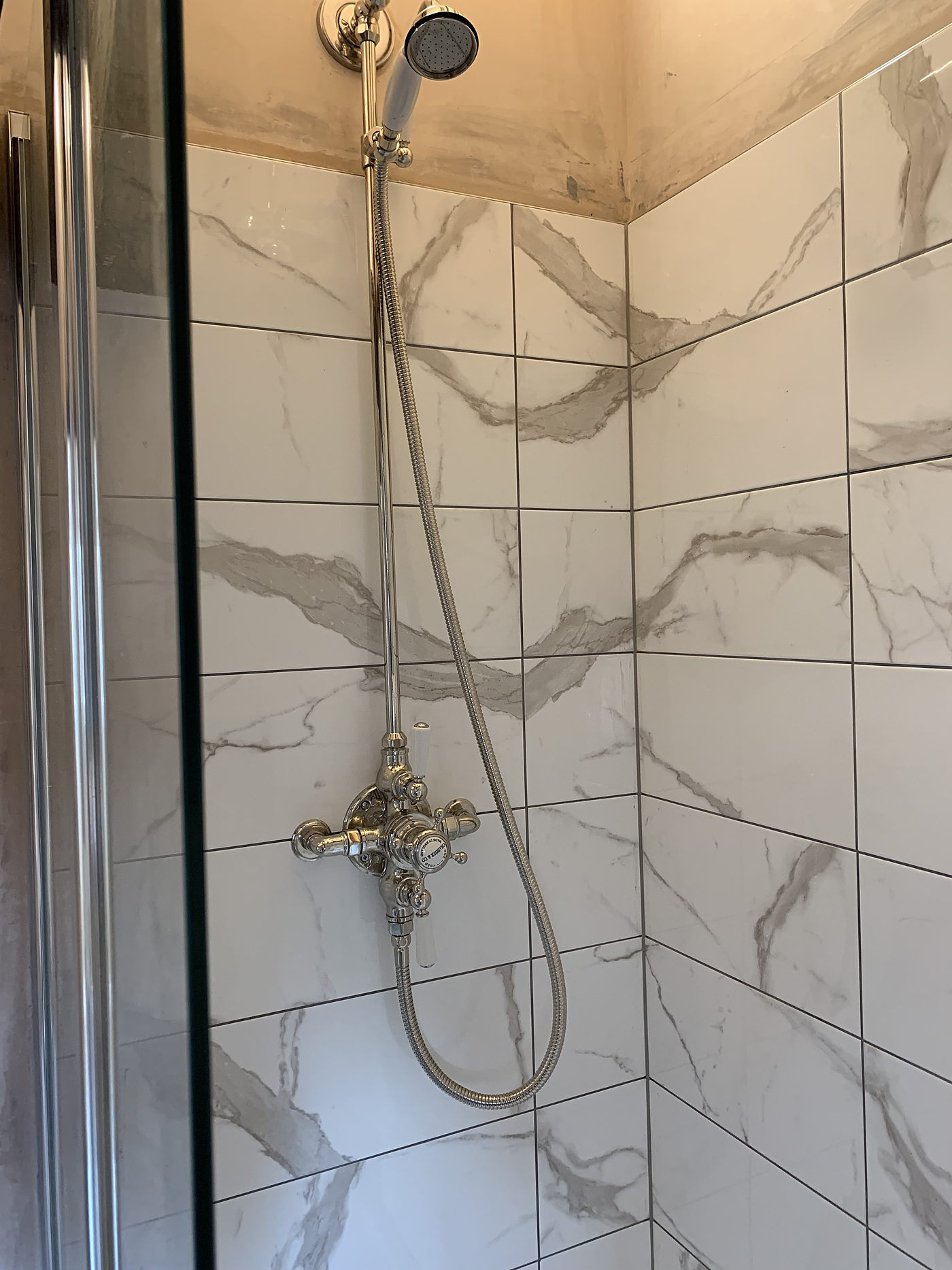 Marble tiled shower with a traditional chrome mixer