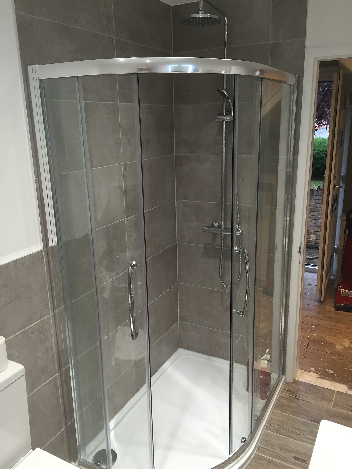 Quadrant shower enclosure in a finished grey tiled bathroom