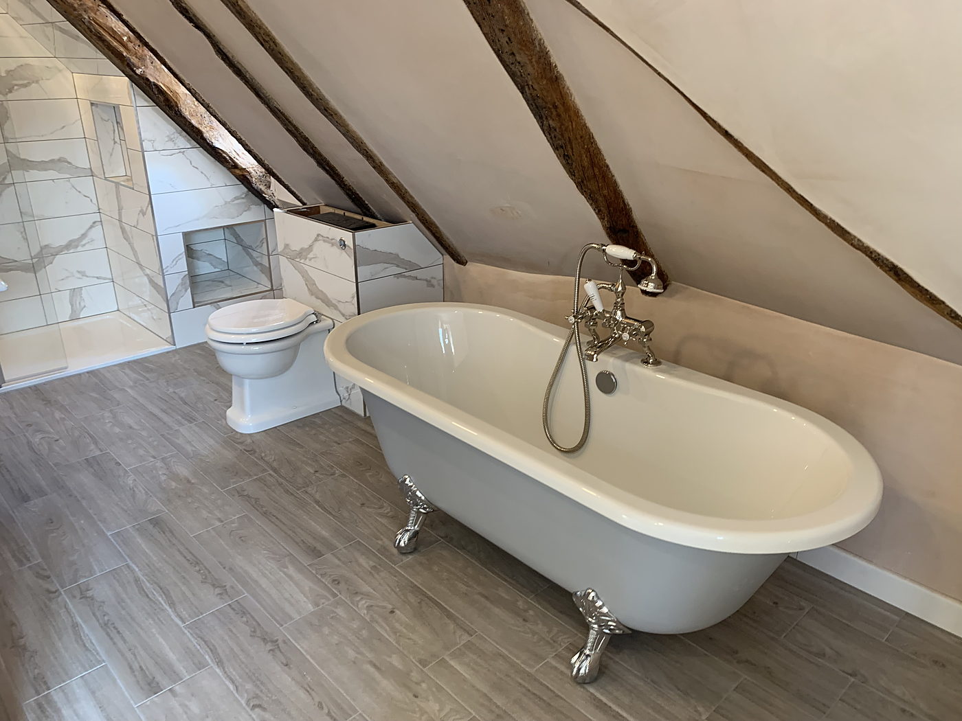 Roll top bath and traditional WC in a beamed bathroom