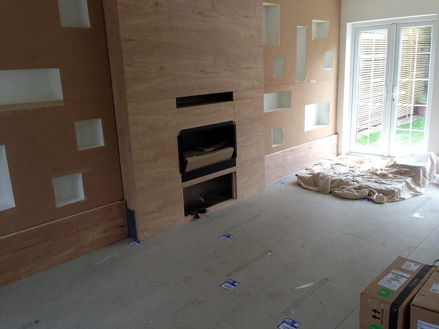 Media wall under construction with inset niches and a fireplace opening